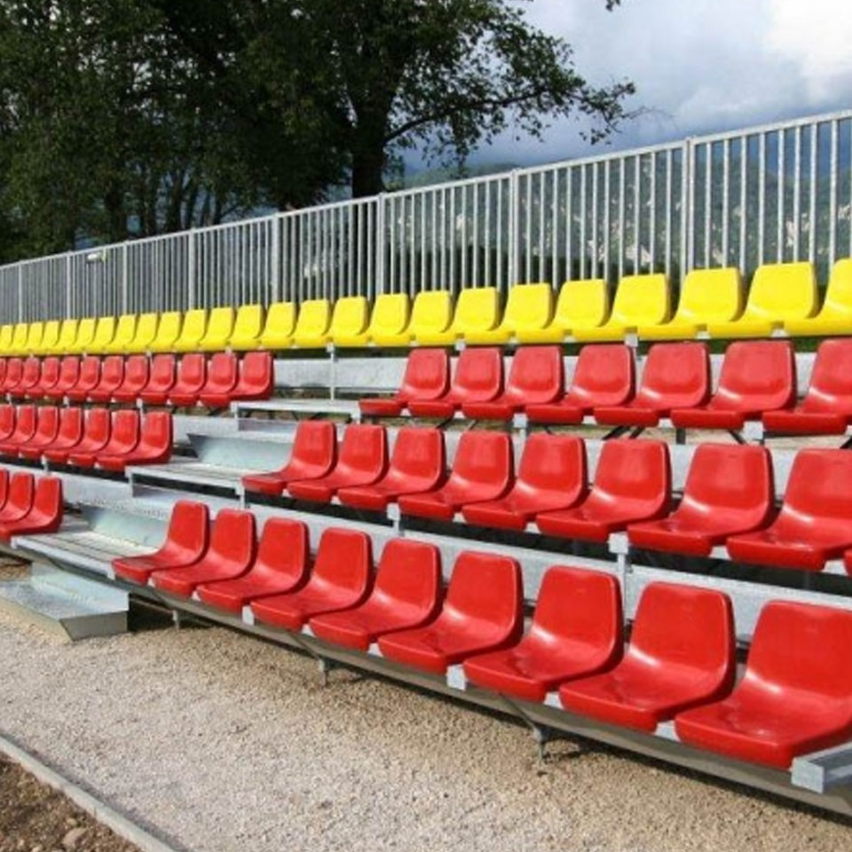 A row of red and yellow auditorium seating in a stadium.