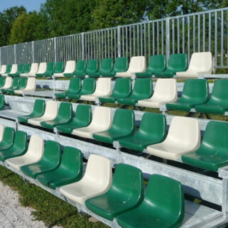 A row of green and white auditorium seating on a grassy field.