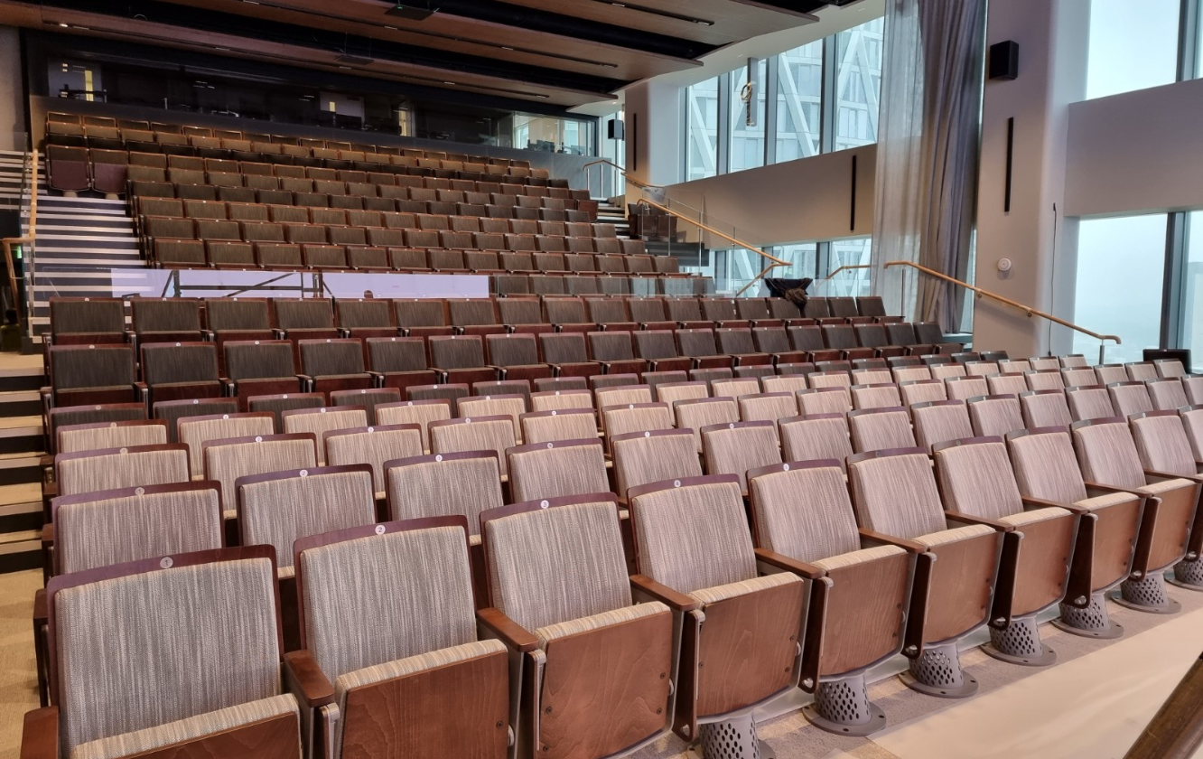 A large auditorium with rows of theater style seating and stairs.