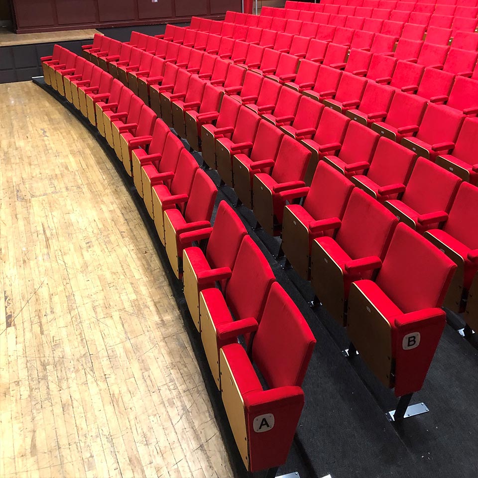 An empty auditorium with red tip up seating
