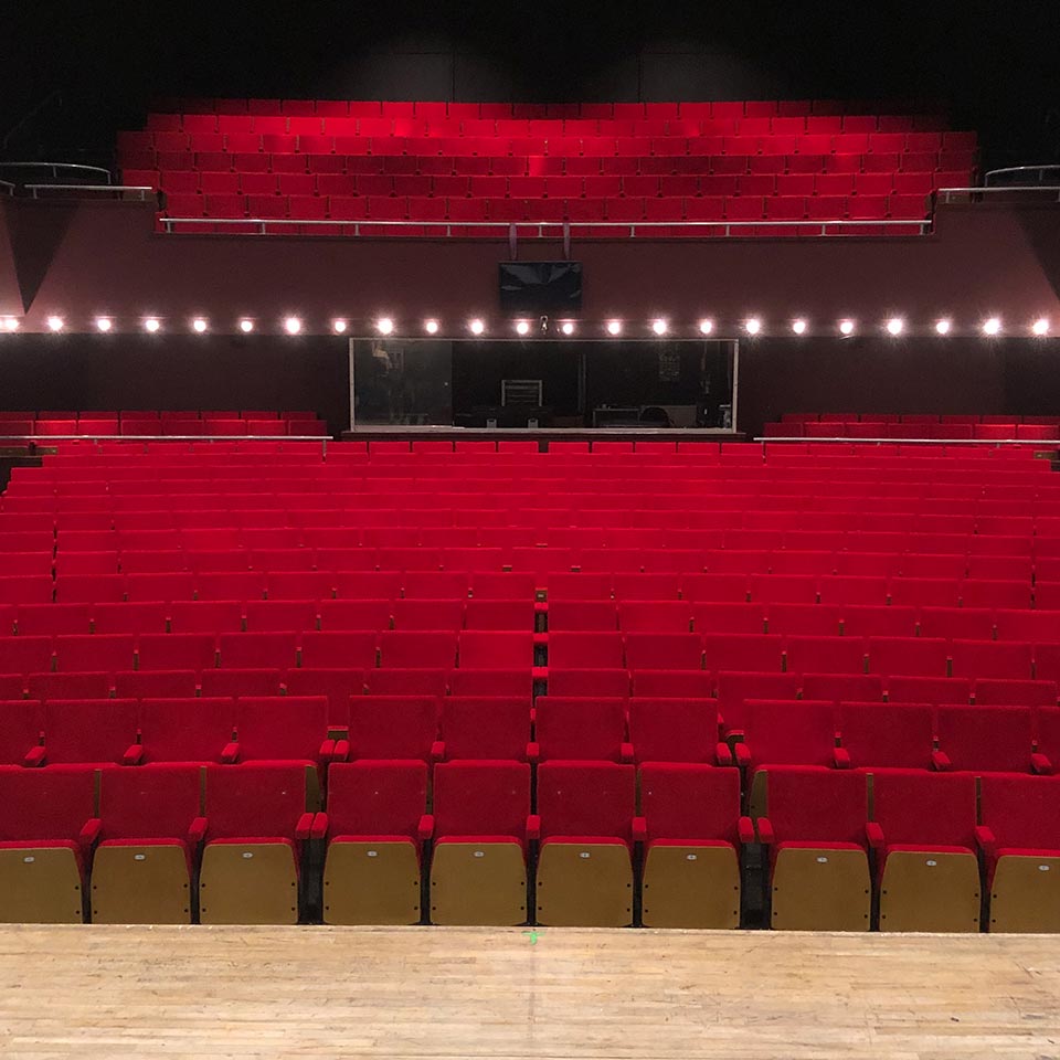 An empty auditorium with red tip up seating