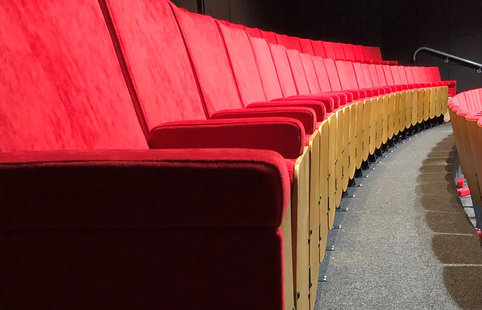 A row of red auditorium seating in an auditorium.