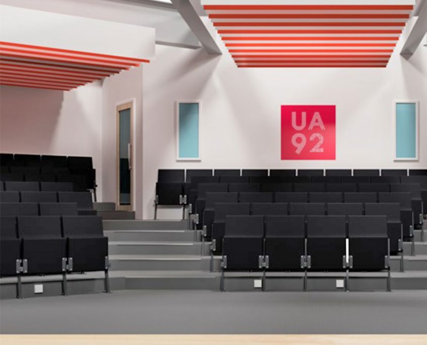 A large auditorium with rows of auditorium seating and a red ceiling.