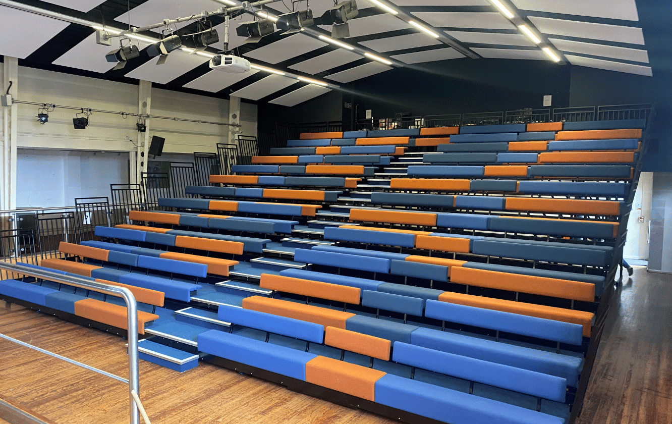 A row of blue and orange auditorium seating in an auditorium.