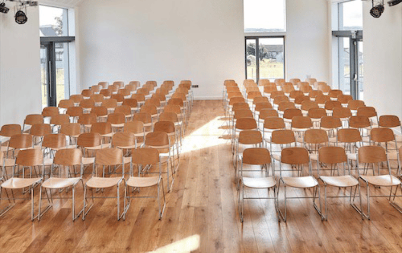 A large room with rows of wooden chairs.