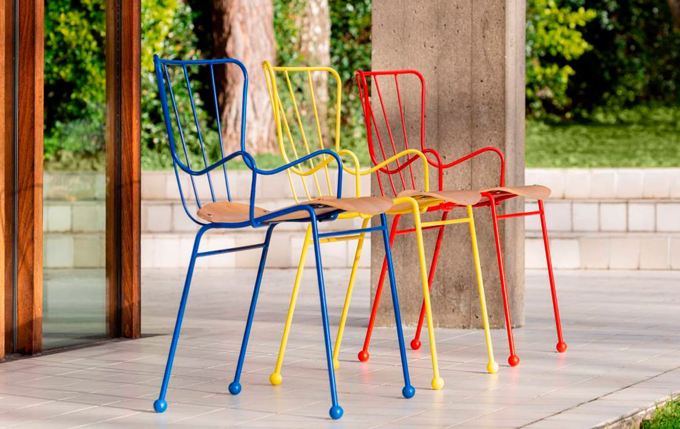 Three colorful metal chairs in front of a patio.