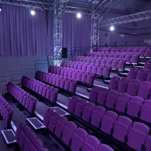 An auditorium with rows of purple retractable seating